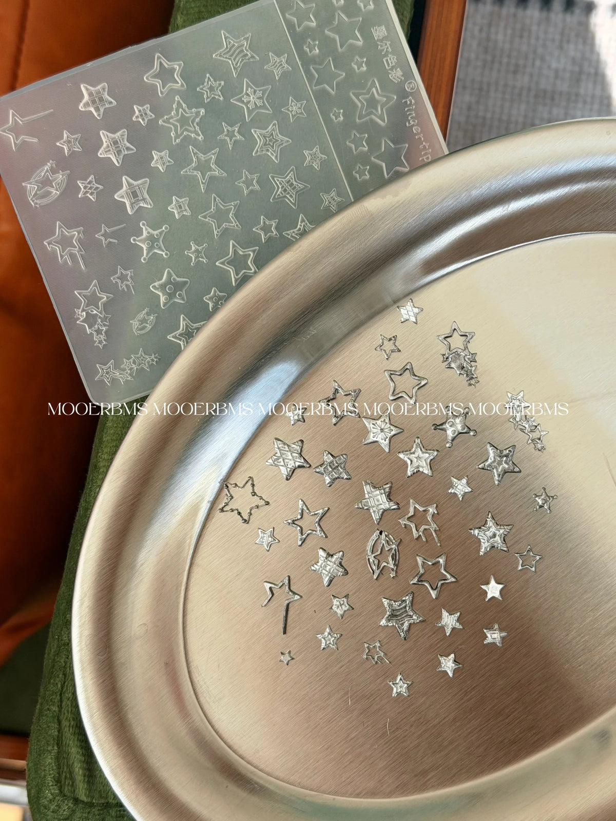 Chrome star charms on a tray beside the silicone mold