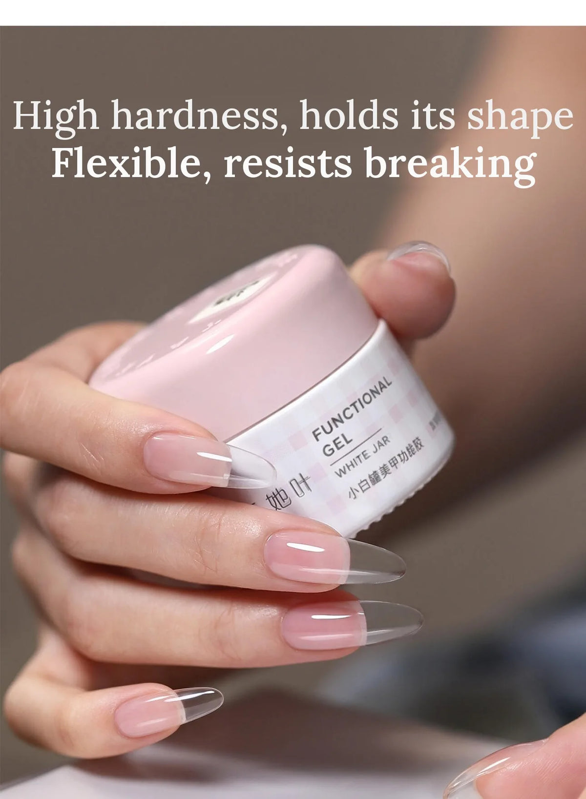 Hand holding the pink TAYE extension gel jar with long clear almond extensions