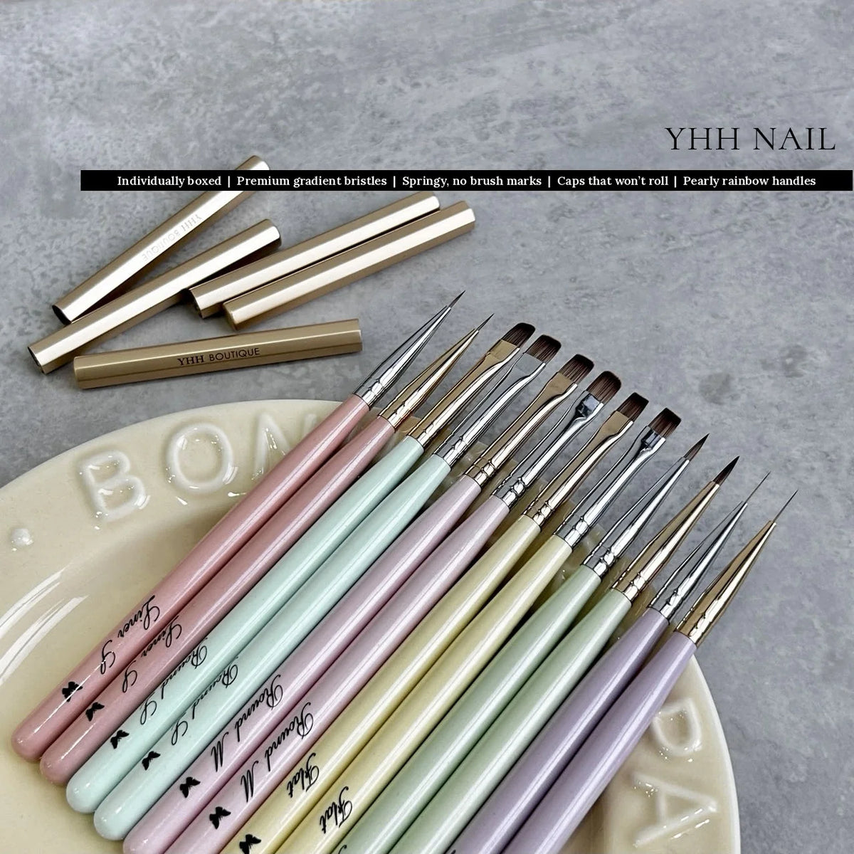 Rows of YHH nail art brushes with pearly pastel handles on a ceramic dish